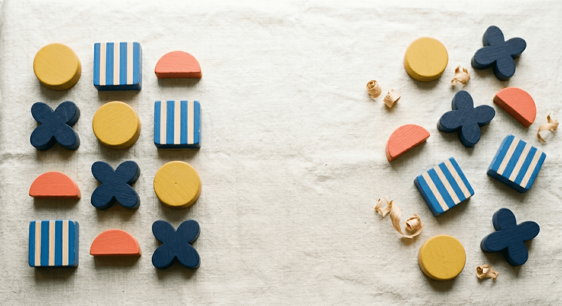 Bauhaus wooden blocks in a neat grid on the left transitioning to scattered sparse pieces on the right on cream linen