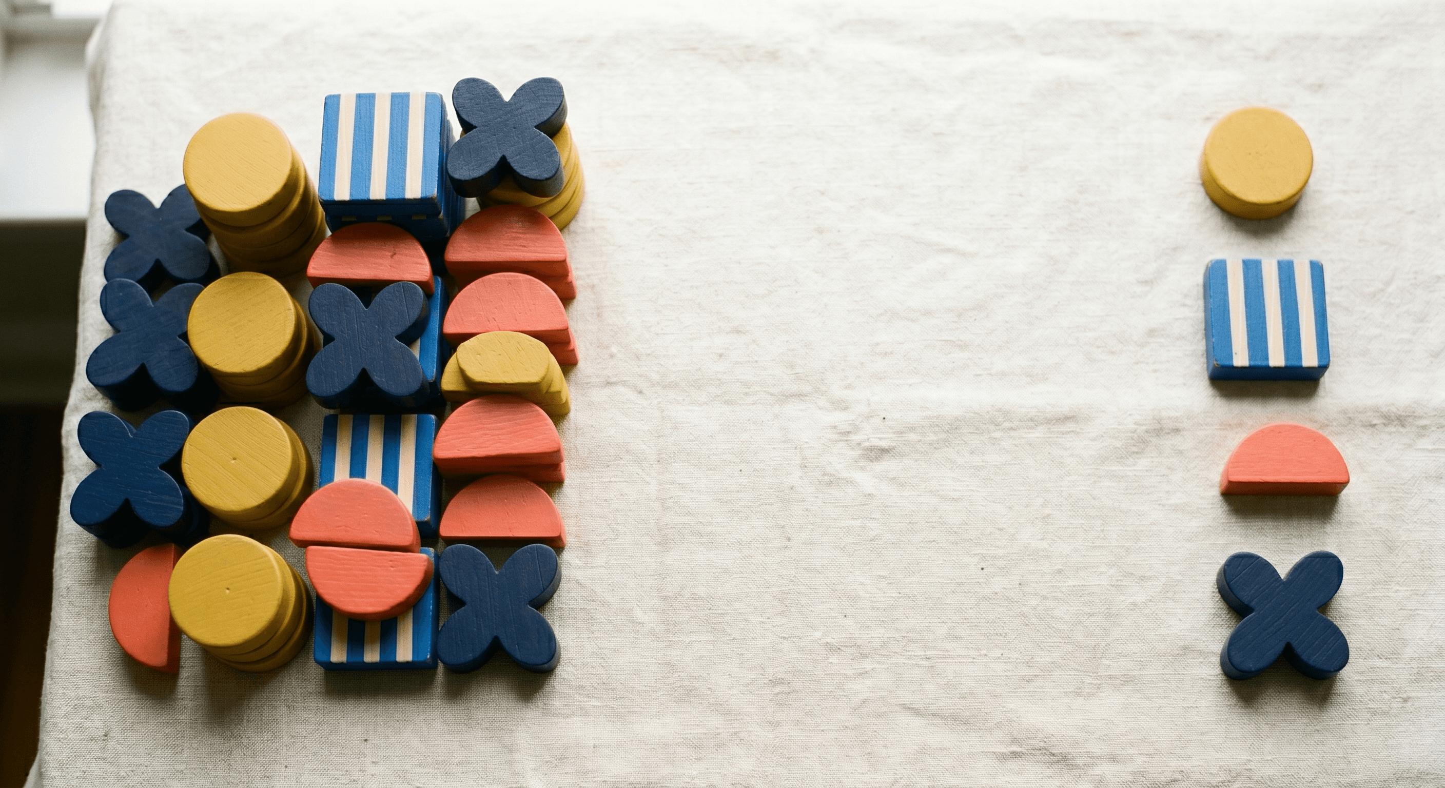 Bauhaus wooden blocks tightly packed on the left with a few pieces spaced out on the right across cream linen